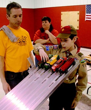 Jacob Neuman, 12, sets his “Cub Ola” car on the top track during the Cub Scout Pack 187's Pinewood Derby competition as his Father, Larry, watches. Complete results of the competition wil be in the Wednesday edition of the Daily Tribune.