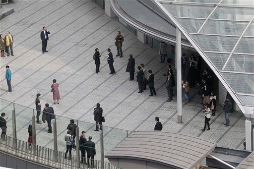 Office workers in Tokyo's Shiodome district near Tokyo Bay stay on the pedestrian deck Friday, March 11, 2011, shortly after a 8.8-magnitude earthquake has struck off Japan's northeastern coast.