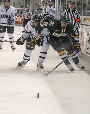 UNH's Jeff Silengo battles for the puck with UVM's Matt Marshall during their game in Durham Friday night.