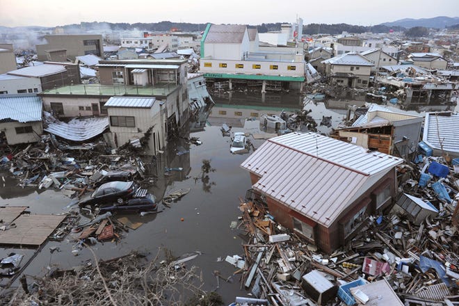 A tsunami-drifted house, bottom right, sits on the debris in Kesennuma, Miyagi Prefecture, Saturday morning, March 12, 2011 after Japan's biggest recorded earthquake slammed into its eastern coast Friday.