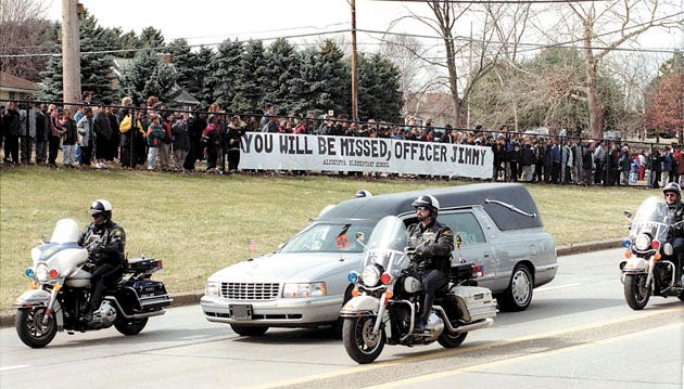The hearse carrying the body of Aliquippa Police Officer James Naim goes past the Aliquippa Elementary School. Students lined the fence overlooking Kennedy Blvd. to see the procession.