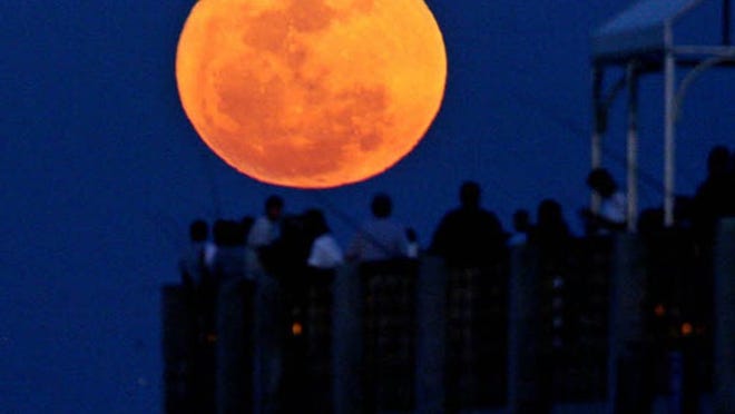 A super "perigee moon"--the biggest in almost 20 years, rises over the pier at the beach while fisherman cast their lines into the Atlantic Ocean in Lake Worth in March 2011.