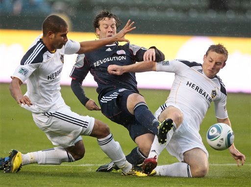 New England Revolution forward Zack Schilawski, middle, battles Los Angeles Galaxy defender Leonardo, left, and midfielder Chris Birchall for the ball during the first half of an MLS soccer match, Sunday, March 20, 2011, in Carson, Calif. (AP Photo/Bret Hartman)