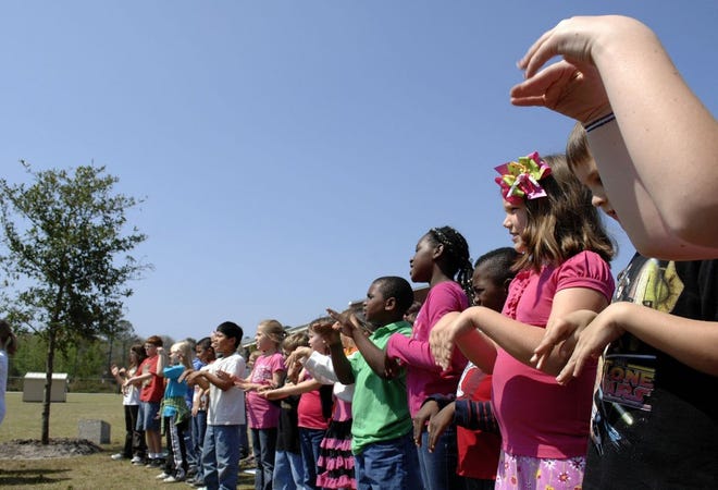 Second-graders at Sterling Elementary sign as they sing "Peace Like a River" Monday at a ceremony to dedicate a live oak, donated by Sea Island Co., in memory of Derek Snyder, who died in January of an asthma attack. The tree was planted next to the school's playground.