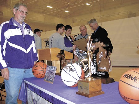 Mike Bosma, a member of the Three Rivers Community Schools Board of Education, inspects the trophies the Three Rivers High School girls’ basketball team captured during its 27-1 season. The 12-member squad was saluted Monday at a community celebration at the high school.