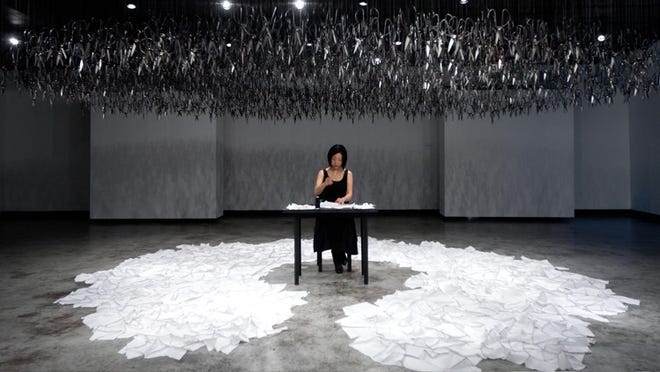 As artist Beili Liu stitches a kind of order together from chaos in 'The Mending Project,' visitors are invited to cut more pieces from a roll of white fabric, adding to the process.