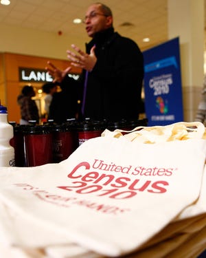 Census employee Mark Correia gives out information and census labeled bags and mugs during a 2010 census event at the Westgate Mall in Brockton Monday.
