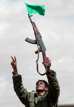 In this image taken during an organized trip by the Libyan authorities, a Libyan supporter of Moammar Gadhafi wearing a uniform displays his new automatic weapon during a staged spontaneous demonstration in Ban-Waled, home of the Warfallah tribe, 160kms (100 miles) south east of Tripoli, Libya, Wednesday March 23, 2011. International airstrikes forced Moammar Gadhafi's tanks to roll back from the western city of Misrata on Wednesday, giving respite to civilians who have endured more than a week of attacks and a punishing blockade.(AP Photo/Jerome Delay)