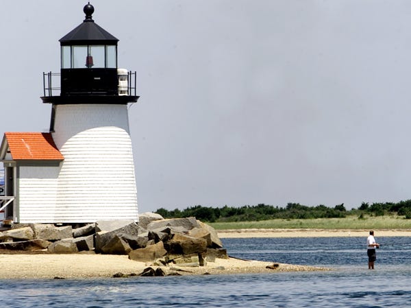A lone fisherman wades out on a sand bar off of Brant Point Lighthouse in the Nantucket Harbor.