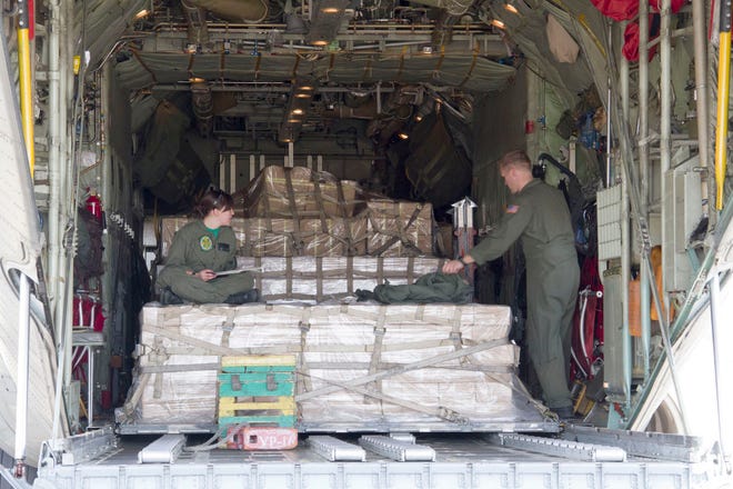 VR-62 loadmasters AWF3 Kayla Ramberg and AWF2 Thomas Beer finish paperwork and cargo checks of Japanese relief supplies in their C-130T Hercules March 19 at Marine Corps Air Station Iwakuni, Japan.