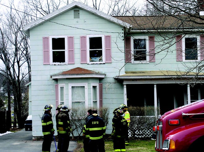 Clifton Springs firefighters gather in the yard at 28 Broad St. in Clifton Springs yesterday after putting out a second-floor bedroom fire that may have started with a lighted candle.