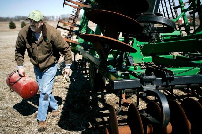Dale Brown walks away from a soil spreader after filling its tires with air Wednesday, March 30, 2011, on his 1,800-acre Rockford farm.