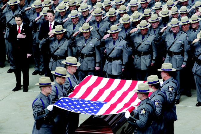 Troopers fold the flag during Friday’s funeral of Trooper Kevin Dobson at the Eastern Hills Wesleyan Church in Amherst, Erie County. Dobson was was hit by a car and killed while writing a traffic ticket.