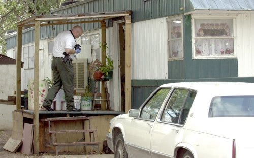 A Potter-Randall Special Crimes officer photographs the murder scene at the mobile home park at 7003 E. Amarillo Blvd. Raul Lozano was shot in the head on Sept. 22, 2004.