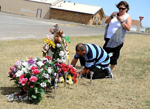Randall Craine plants flowers Sunday as Josie Craine takes a photo with her phone of the memorial for their only son, Salomon, who was killed in a car wreck Sept. 6 at Maryland Street and Amarillo Boulevard. The Craines come out every other Sunday to ref