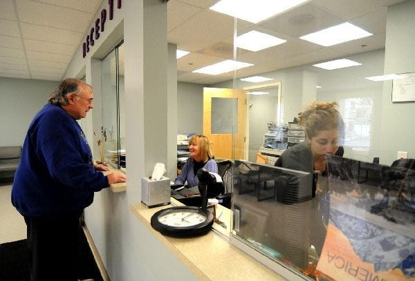 Robert “Bach” Charon of Orleans checks in with receptionist Barbara Silvia at the Duffy Health Center's new location Monday morning. Charon is a client and board member of the center, which offered some limited services Monday.