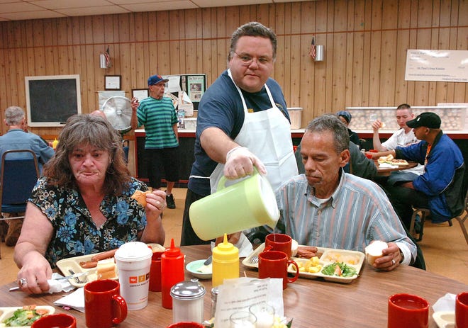 Carol Brady and Bryan Nolette are served food and drink by volunteer Bob Moriarty at the St. Paul’s Episcopal Church soup kitchen on Pleasant Street in downtown Brockton.