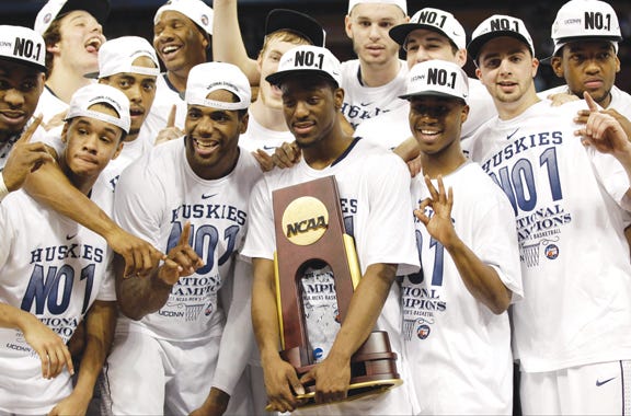 Connecticut players celebrate with the trophy after the men's NCAA Final Four college basketball championship game against Butler Monday in Houston. Connecticut won 53-41.