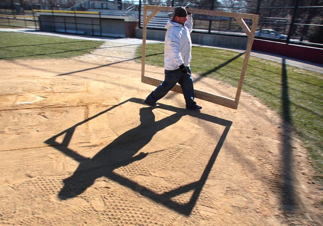 Steve Zambruno of the Quincy Parks and Forestry Department carries a batter’s box template to home plate at Adams Field.