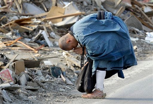 A Buddhist monk Sokan Obara, 28, from Morioka, Iwate Prefecture, prays for the victims in the debris in the area devastated by the March 11 tsunami in Ofunato, Iwate Prefecture, Japan.