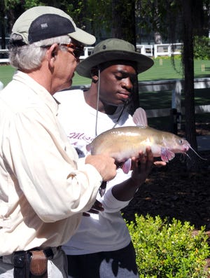 Fuzzy Davis, director of outdoor pursuits at the Ford Plantation in Richmond Hill, shows 17-year-old Rasheik Wilson how to hold a catfish Thursday morning. Wilson and other members of the Bethesda Home for Boys' wildlife management program spent the morning fishing and learning about catfish. In all, the boys caught more than 100 fish. The group held a fish fry at the school later in the day. (Corey Dickstein/Bryan County Now)