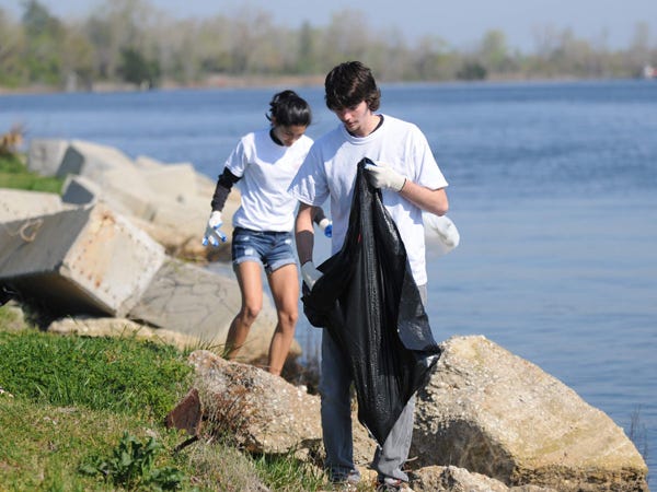 Volunteers pick up trash at Battleship Park during the 12th annual Azalea Pride event .