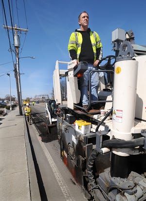 Paul Fyfe of Lorusso Corporation in Plainville operates a grinding machine on Waverly St. in Framingham Saturday morning as Framingham DPW workers prepared the road for the Boston Marathon. The DPW will return on Monday to repave .