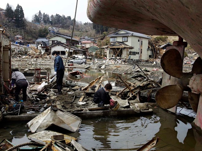 A Japanese family, who refused to give their family name, cleans an area around their house next to the grounded ship at an area devastated by the March 11 earthquake and tsunami in the port town of Kesennuma, Miyagi prefecture, Japan, on Monday, April 11, 2011. (AP Photo/Sergey Ponomarev)