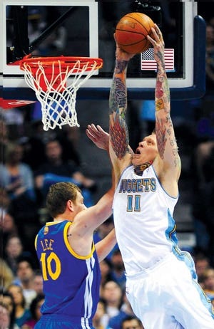 Denver Nuggets forward Chris Andersen dunks over Golden State Warriors forward David Lee in the first quarter Monday in Denver. The Nuggets exploded in the second half to win 134-111.