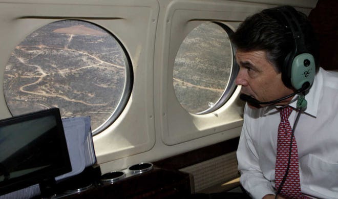 Texas Gov. Rick Perry looks at an area burned by wildfires during a low-altitude jet tour of Stonewall County near Swenson on Tuesday.