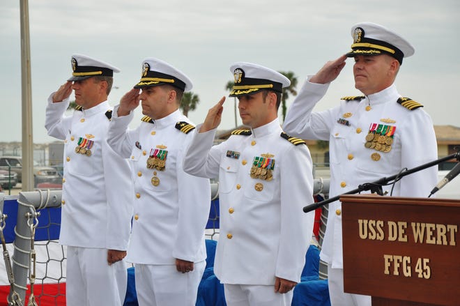 Outgoing USS De Wert Commanding Officer, Cmdr. Sean McLaren, third from left, is joined by incoming commanding officer, Cmdr. Vince Baker, second from left, Chaplain Peter Dietz, far left, and DESRON 14 Commodore, Capt. Gary Haben, in a salute during the Pledge of Allegiance at De Wert's change of command ceremony on April 7.
