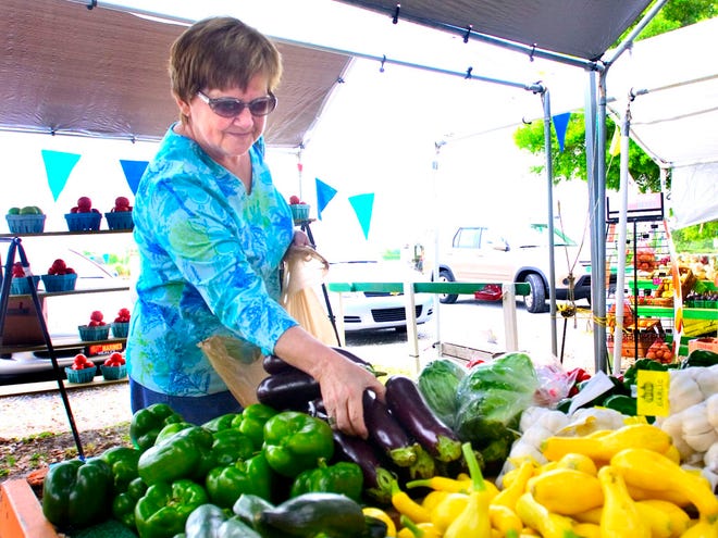 A customer sorts through the produce at the Farmers Market on West Highway 200 in Ocala.