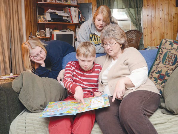 Autum Fairman, 13, and Amber Fairman, 17, look on as brother Austin and their mother Charlene Fairman read a book in their living room. The family relies on programs and services from Happiness House and Ontario ARC.