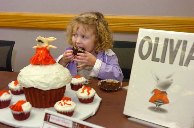 Jane Reall, 3, of Mount Laurel, eats a cupcake near her entry in the edible cake/book contest.