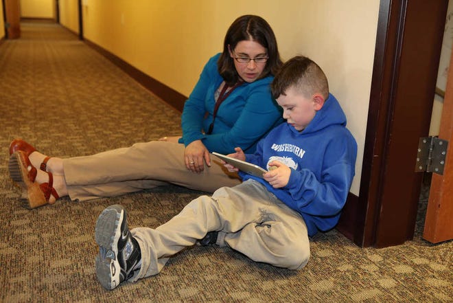 Kindergartener Lucius Rice, 6, and literacy teacher Maurie Dufour look at a book on an iPad on Tuesday in Auburn, Maine. Five teachers were given iPads to try out in preparation for next year when nearly 300 kindergarteners will be given their own iPad2s.