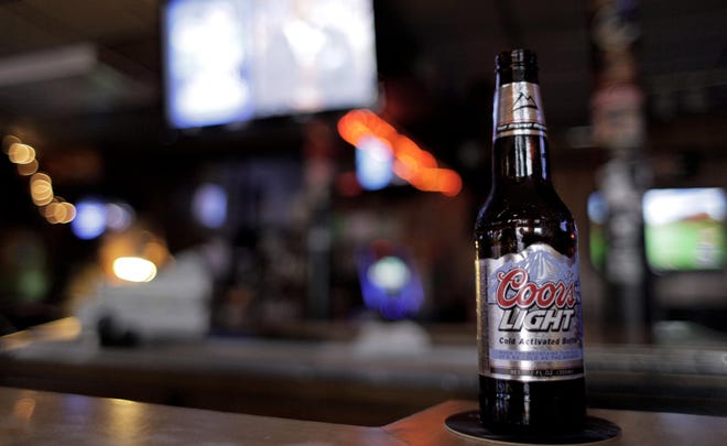In this Feb. 6, 2011 photo, a bottle of Coors Light rests on the bar at 'Kevin and Kathy's Pub Time', in Blue Island, Ill. Molson Coors Brewing Co. said Thursday, Feb. 10, its net income fell 51 percent in the fourth quarter as it sold less beer and dealt with rising costs for taxes, ingredients and fuel.(AP Photo/M. Spencer Green)