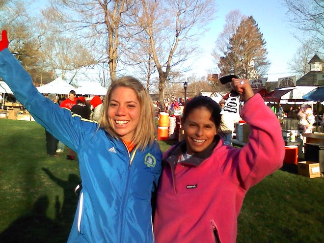 Janelle Cunningham, left, of Waltham, and Deb Peak, of Millbury, are psyched to run the 115th Boston Marathon as they wait on the Hopkinton town green before 7:30 a.m. - about 3 hours before they'll start running 26.2 miles.