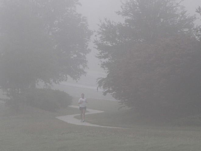 A jogger runs through fog in a park at Southeast 32nd Street and Southeast 18th Avenue in Ocala. (Doug Engle/Staff photographer)