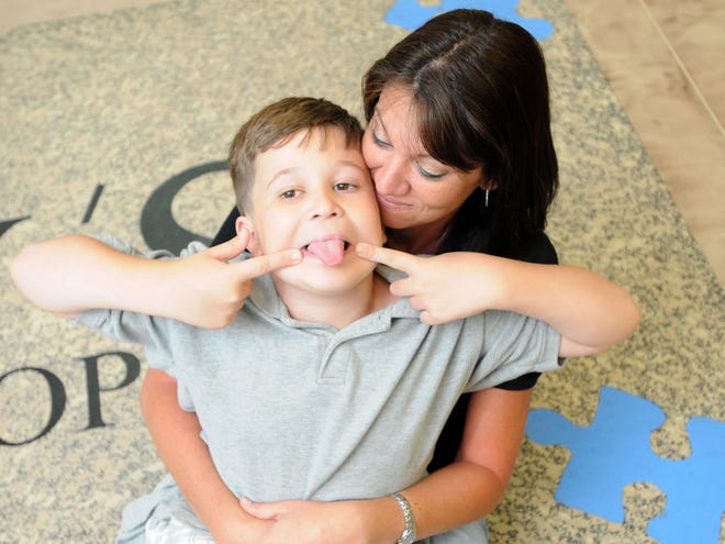 Stacy Gerrity-Sansevere, owner of Stacy's Barbershop, plays with her 10-year-old son, Garian, at the shop in Ocala on April 12. Garian is autistic and the shop is hosting an autism awareness essay contest for children through the end of April.