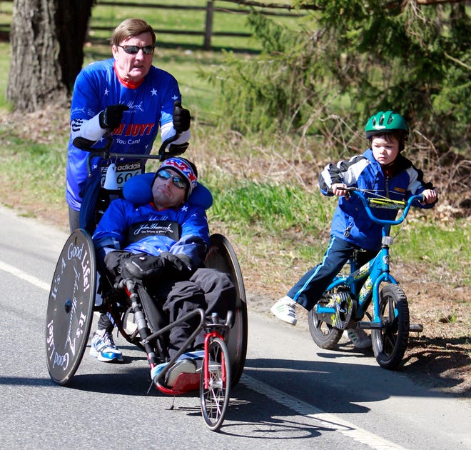 Dick Hoyt and his son Rick of Holland pass a small boy on a bicycle during the 115th running of the Boston Marathon.