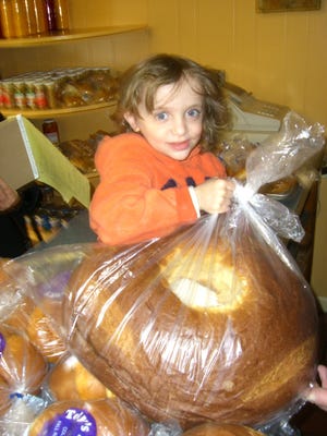 Andrew Rioux, 3, hoists a large sweet bread ring, which contains six baked eggs, at Tony's Bakery in Fall River.