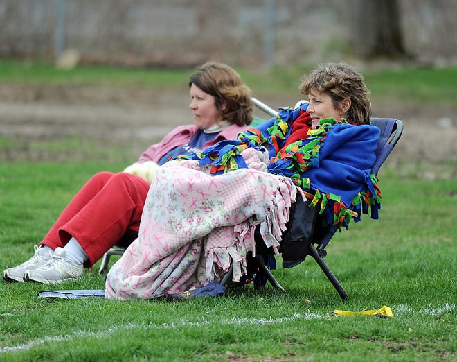 Diane Casey, right, and Laureen Pratt, both of Milford, watch the Milford High School baseball game against Tantasqua at Fino Field where the temperature was in the 40s. (Daily News photo by Lisa Cassidy)