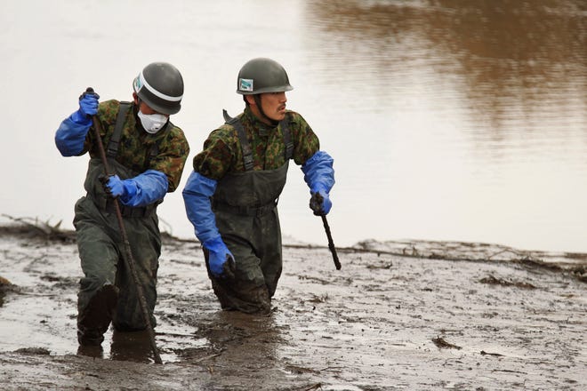 Japanese soldiers search for bodies near the town of Shichigahamamachi