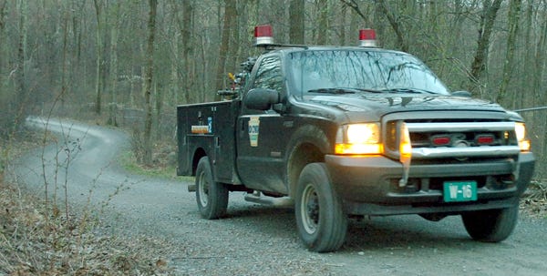 A Department of Conservation and Natural Resources vehicle leaves the scene off Raspberry Run Road in Lehman Township where a man was found dead in a creek Tuesday evening.