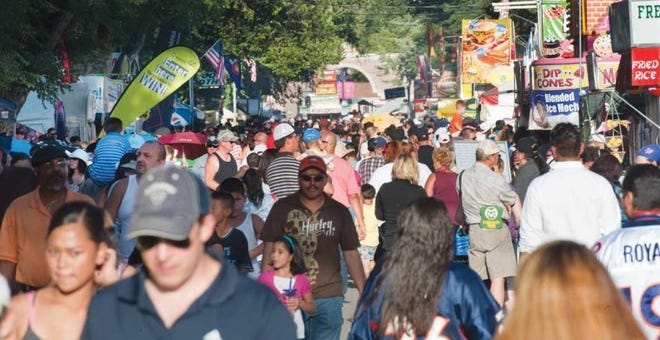 Visitors walk along a street during last year's Colorado State Fair. The state's population keeps growing despite few new jobs, analysts say.