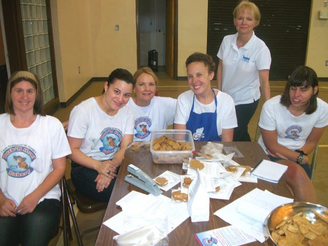 Jennifer Johnson (front, from left), Angie Matos, Jessica Bartlett and Erin Nowikowski display the results of their culinary skills at the Bark 'N Howl Bakery, a non-profit where developmentally challenged young adults learn vocational skills by baking and selling gourmet dog treats. Nowikowski is the top seller. At rear are co-founders Martha Sawyer (kneeling) and Leigh Forrester.