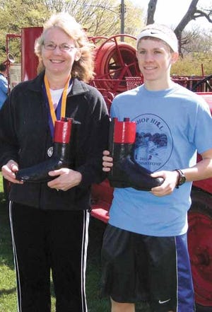 Patty Gustafson, left, and Derek Foley display the wooden-boot trophies they earned for winning Swedish Stomp titles Saturday in Bishop Hill.