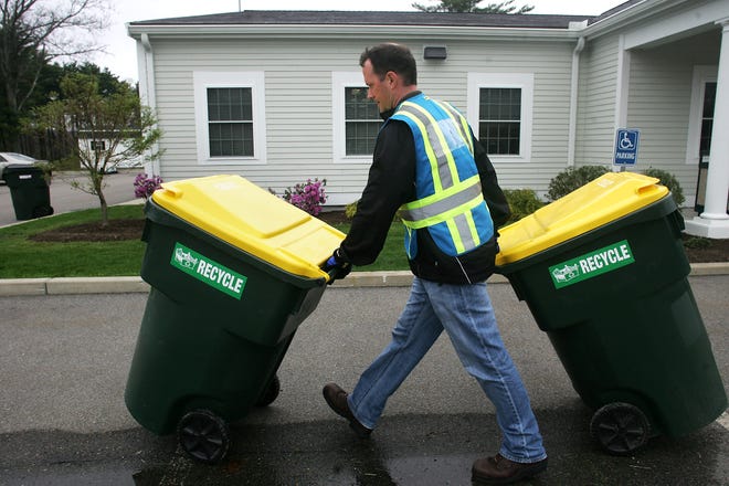 Kevin O'Grady, a route manager from Waste Management Inc. working with Franklin, returns recycling bins to the area next to the town's DPW office following a trash removal demonstration yesterday. Franklin received an $86,500 state grant, which the town will use to help offset the cost of wheeled carts for its collection program.
