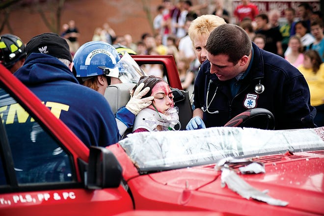 Photo by Jesse Murch/New Jersey Herald 
Members of the Newton EMT secure and help a Newton High School drama club student who was “hurt” in a “drunken driving accident” staged at the school.