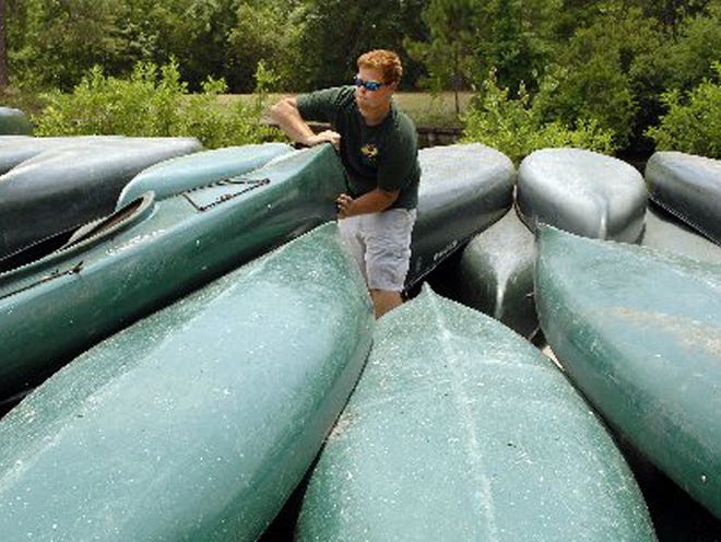 Jared Renshaw stacks Okefenokee Adventures canoes between the Suwannee Canal boat basin and the parking lot. The canoes had been in the edge of woods, so Renshaw moved them to get them out of the reach of the Honey Prairie Fire.